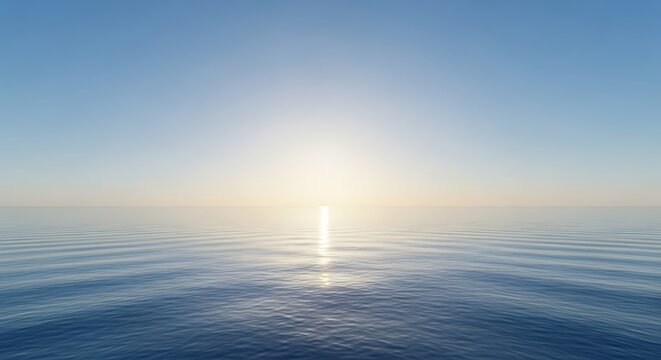Calm ocean water reflecting sunlight under a clear blue sky during a peaceful and serene sunrise