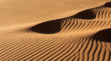 Close up view of sand dunes with visible wind patterns and shadows creating a textured landscape