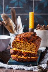 Pumpkin raisin bread with icing, served with tea on a dark background.