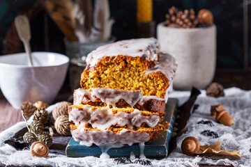 Pumpkin raisin bread with icing, served with tea on a dark background.