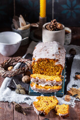 Pumpkin raisin bread with icing, served with tea on a dark background.