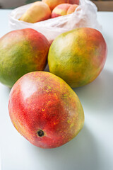 Spontaneous shopping scene where ripe mangoes and juicy peaches create interesting volumes inside translucent plastic bags