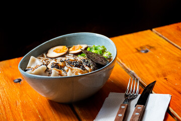 ramen bowl with nikuman giosa and smoked eggs close up at angle on black background