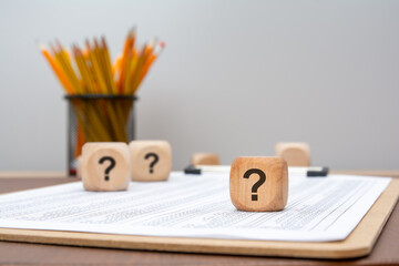 wooden cubes with question marks on financial report, symbol of doubt or uncertainty