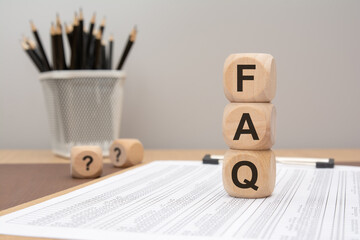 wooden cubes spelling FAQ placed on printed document