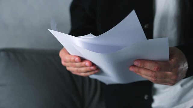 A secretary rolls up a white sheet of paper in her hands.
A bundle of paper and important documents are in a person's hands.
Signing a contract and reading information.
Office, work, taxes, contract