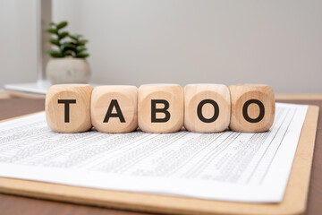 wooden cubes with the word TABOO on financial spreadsheet, concept of forbidden topics