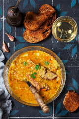 Lentil soup with pork and vegetables, served with white wine and croutons.