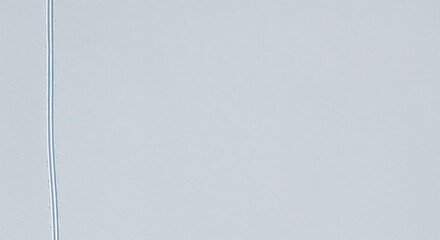 A clean, wide overhead view of a distinct cross-country ski track gracefully traversing a flat, expansive, light blue winter landscape under bright, even lighting.