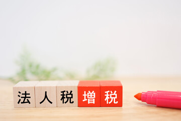 法人税増税を示す木製ブロック。白背景。コピースペースあり。