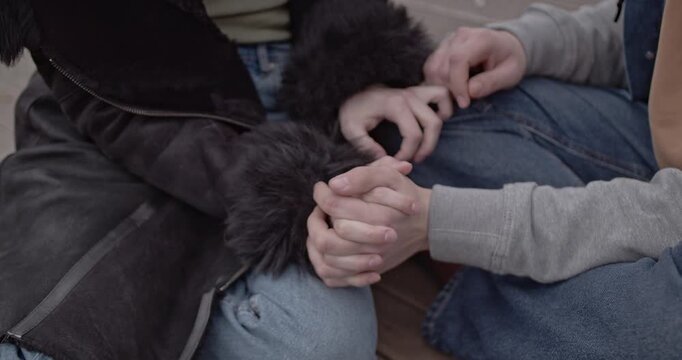 Close-up of a couple's hands gently intertwined, showcasing a deep emotional bond and tenderness.