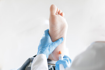 Podiatrist treating patient foot with medical tools in clinical setting