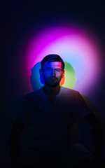 Portrait of a squinting man in neon colorful light.