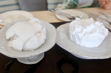 Appetizing white coconut cake is served alongside a scoop of cold, refreshing coconut ice cream, creating a sweet and satisfying tropical dessert.