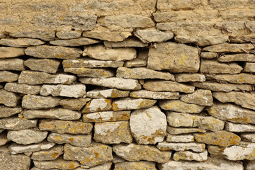 Aged natural stone wall showing rustic masonry texture and old weathered rock background pattern for architecture and design