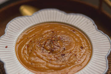 Creamy pumpkin or lentil puree soup topped with red chili flakes and black pepper, serving healthy comfort food