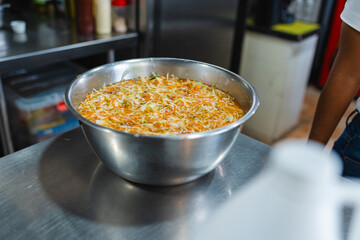 Large metal bowl with shredded vegetables in kitchen