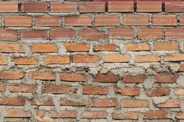 Exposed Clay Brick Wall: Rustic Texture with Different Shades of Red and Orange and Irregular Mortar Joints.