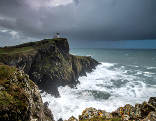 Obraz premium Lighthouse on cliffside overlooking ocean in stormy weather