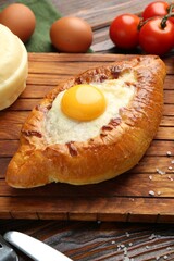 Tasty khachapuri with cheese and other products on wooden table, closeup