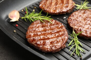 Pan with grilled patties and spices on grey table, closeup