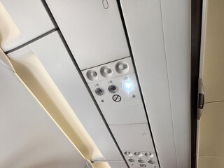 Aircraft cabin ceiling panel featuring overhead lighting controls, air vents, and safety indicators, showcasing modern aviation design and functionality in a travel environment