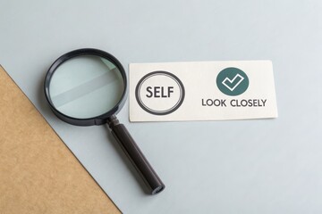 Magnifying glass focusing on the word Self with a checkmark