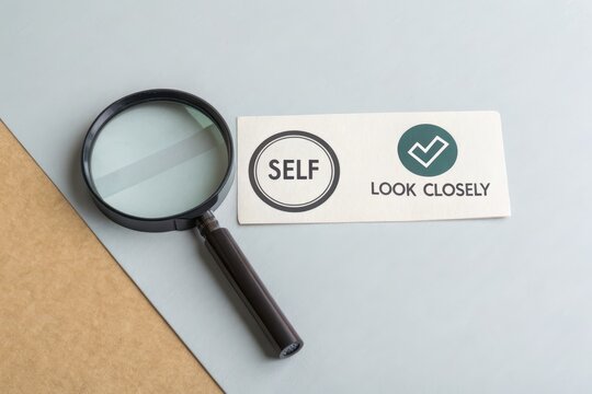 Magnifying glass focusing on the word Self with a checkmark