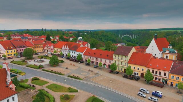An aerial view showcases the picturesque historic town square of Bechyně, Czech Republic, with its colorful buildings and the iconic Duha Bridge Rainbow Bridge spanning the Lužnice River valley in the