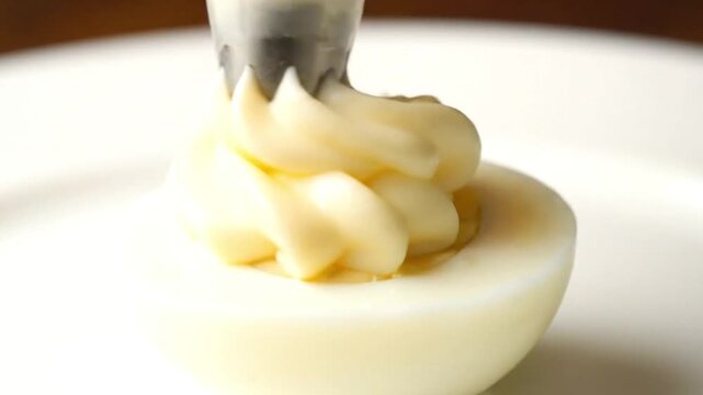 Half of a deviled egg topped with piped filling on a white plate