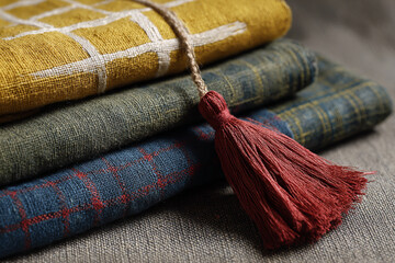 Stack of textured fabric with a red tassel detail