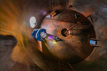 Male worker inspection floor scan tank oil of rust wall, loss of thickness bottom plate in the manhole tank to work inside