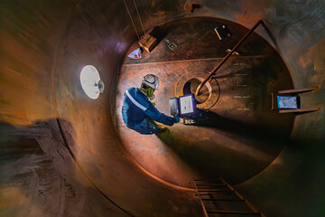Male worker inspection floor scan tank oil of rust wall, loss of thickness bottom plate in the manhole tank to work inside
