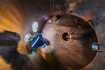 Male worker inspection floor scan tank oil of rust wall, loss of thickness bottom plate in the manhole tank to work inside