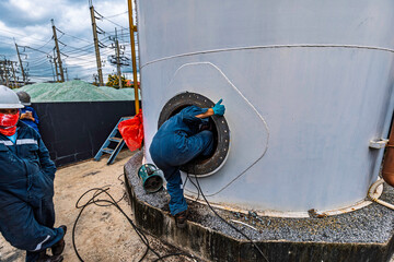 Male worker into the tank carbon chemical oil interface area confined