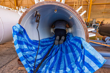 Male worker inspection tank oil of rust wall, loss of thickness bottom plate in the manhole tank to work inside