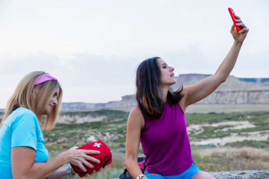 Injured hiker seeks phone signal while companion prepares first aid. Lifestyle. Hiking. Bardenas.