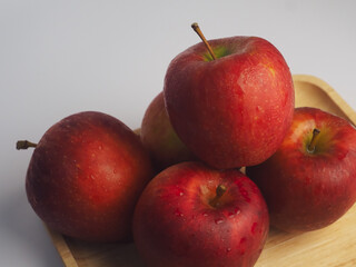 Fresh red apples on a wooden tray, close-up