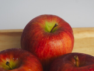 Fresh red apples on a wooden tray, close-up