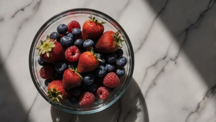 Fresh Berries in a Glass Bowl on Marble Surface.