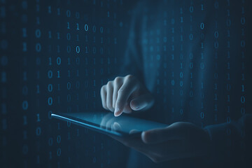 Human hand interacting with digital tablet on dark background surrounded by binary code patterns symbolizing data analysis