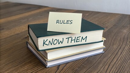 Stack of Books with Sticky Note Reading "Know Them" and "Rules" on Wooden Table for Education and Learning Concept