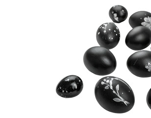 Black Easter eggs, decorated with white floral patterns, clustered in a loose pile against a black background