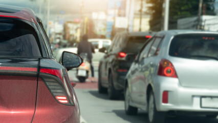 Rear side of red car on body wiht many dust. Turn on brake light line up and wait for the traffic light at the intersection.Backgroundo of intersection with cars driving through and town at day.