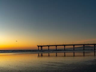 Obraz premium Vertical panorama of pier during sunrise on beach 