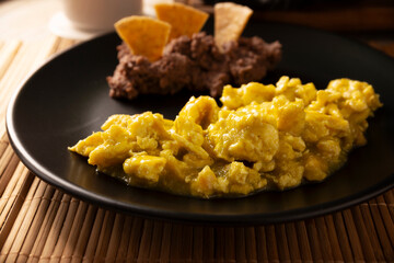 Scrambled eggs in green sauce. A typical Mexican breakfast of scrambled eggs tossed in spicy green sauce, usually accompanied by beans and pot coffee.