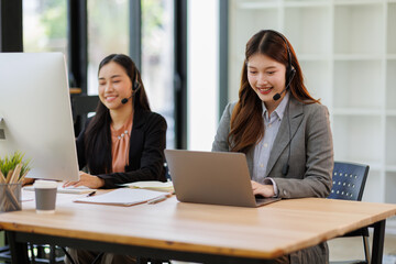 Call center, in headphones. two asian women are working in the office.
