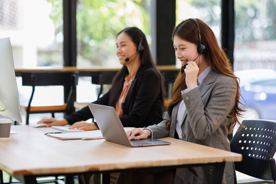 Diverse group of people work at call center or helpful customer service. Attractive women uses pc computer and monitor at busy agency office closeup. Phone talk and answer questions on modern hotline
