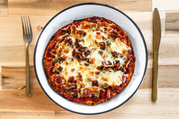 small homemade vegan meat-lover pizza on wooden dining table, healthy vegetarian food
