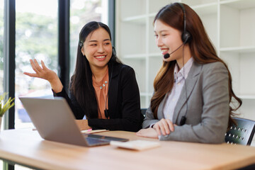 Call center, in headphones. two asian women are working in the office.
